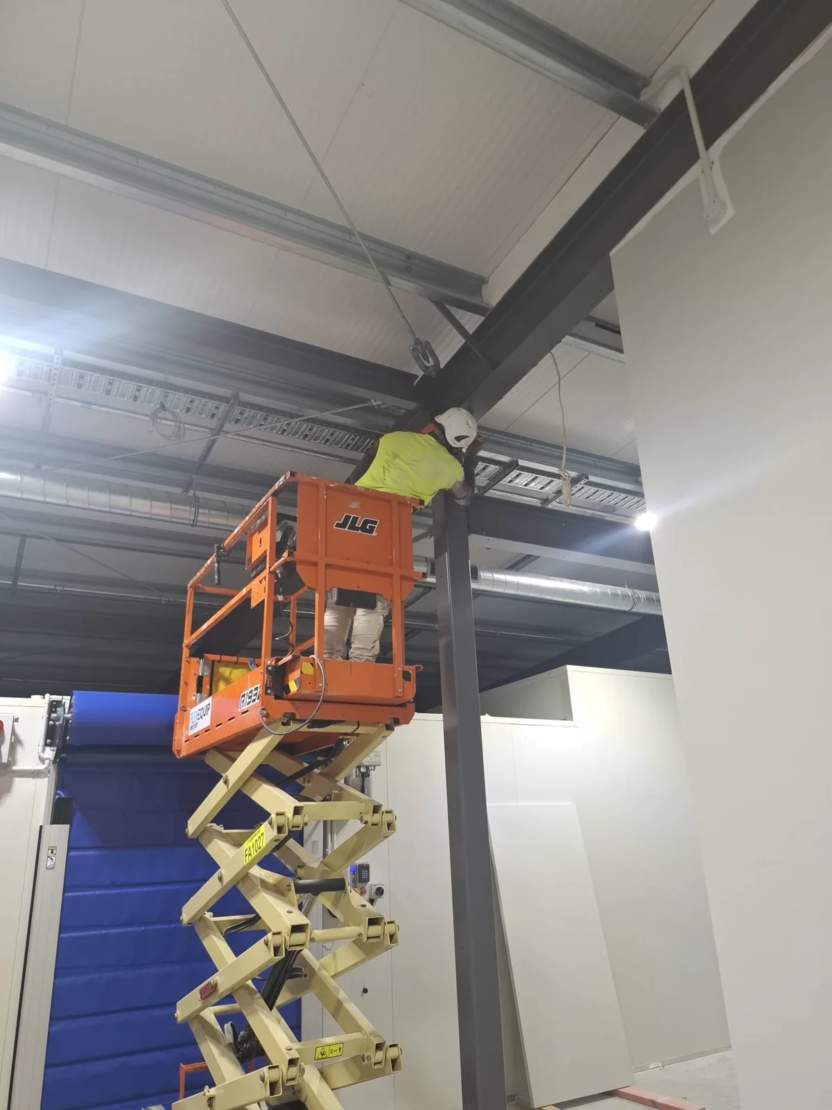 Painter coating structural steel from a scissor lift